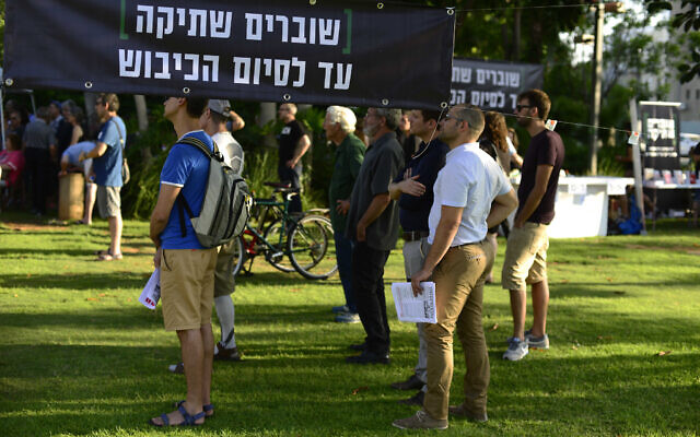 Left-wing NGO Breaking the Silence holds an event in Tel Aviv on July 1, 2017 where testimonies of former soldiers stationed in the West Bank were  read aloud in front of the Kirya military base. The sign reads: 'Breaking the silence until the occupation ends.' (Tomer Neuberg/Flash90)