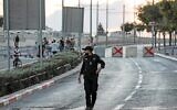 Illustrative: An Israeli policeman walks near cement cubes placed as a roadblock by Israeli security forces on a road linking the East Jerusalem Arab neighborhood of Beit Hanina with West Jerusalem on September 15, 2021 (Ahmad GHARABLI / AFP)