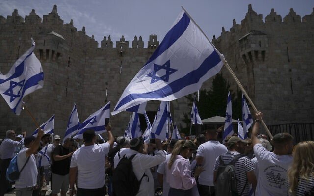 Israelis wave flags ahead of a march marking Jerusalem Day, in front of the Damascus Gate of Jerusalem's Old City, May 18, 2023. (AP Photo/Mahmoud Illean)