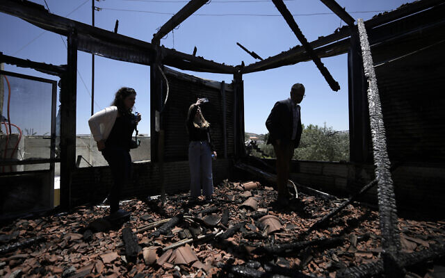 An international delegation examines a torched building as they tour the West Bank town of Turmus Ayya, days after a rampage by Jewish settlers, June 23, 2023. (AP Photo/Majdi Mohammed)