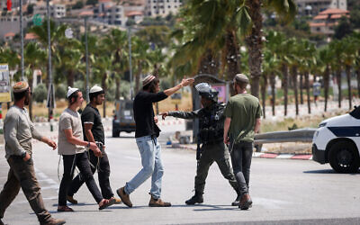 Israeli soldiers and settlers at the entrance to the West Bank town of Turmus Aya, June 21, 2023. (Yonatan Sindel/FLASH90)